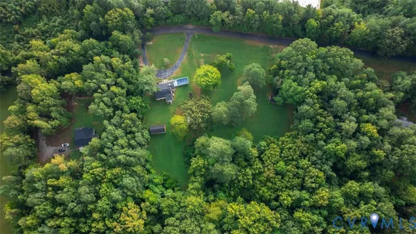 an aerial view of green landscape with trees houses and lake view