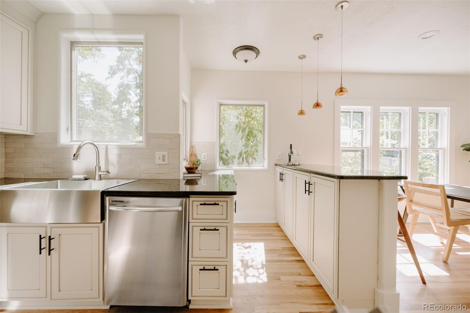 836 9th Street Boulder, CO 80302 - Photo 11 of 32 a kitchen with stainless steel appliances granite countertop a stove a sink and white cabinets with wooden floor