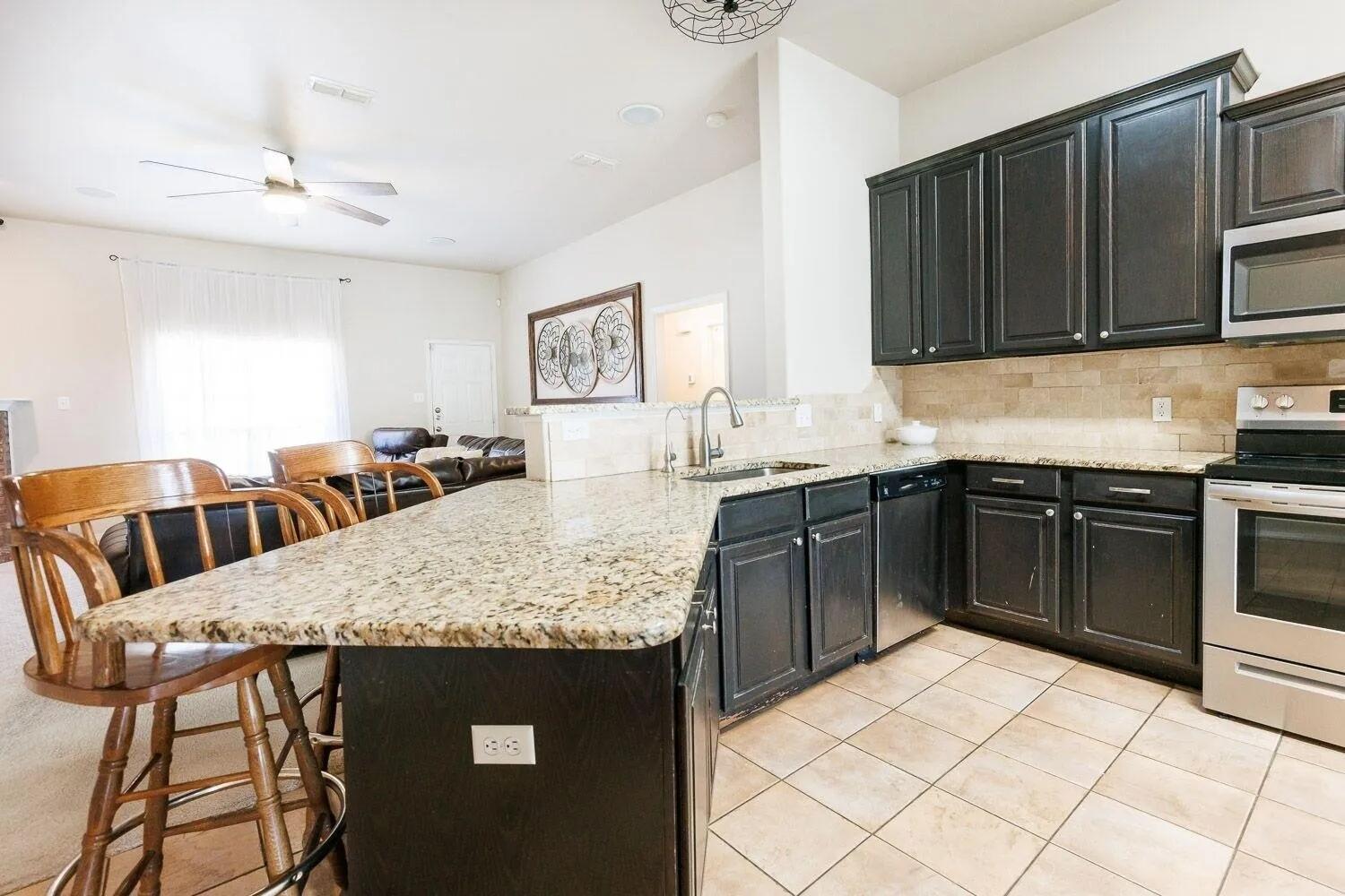 10602 Clinton Avenue Lubbock, TX 79424 - Photo 11 of 36 a kitchen with granite countertop a sink cabinets and stainless steel appliances