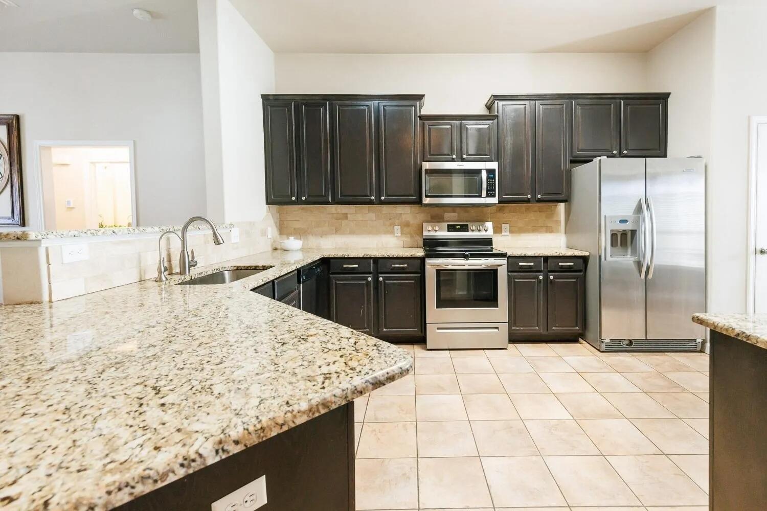 10602 Clinton Avenue Lubbock, TX 79424 - Photo 12 of 36 a kitchen with kitchen island granite countertop a sink stove and refrigerator