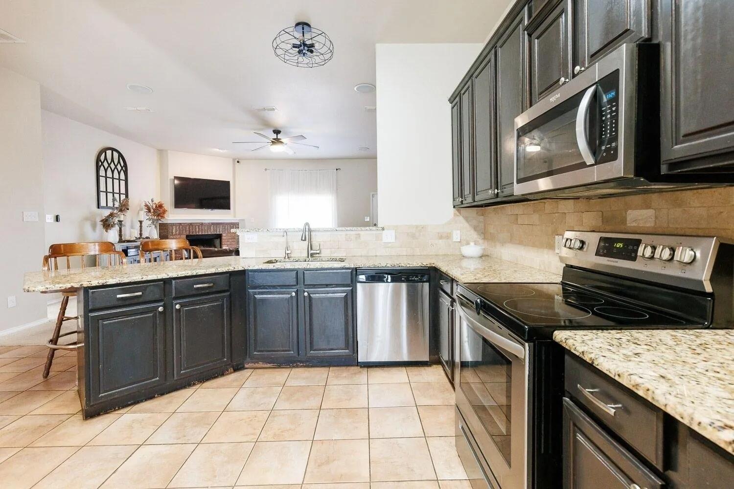10602 Clinton Avenue Lubbock, TX 79424 - Photo 13 of 36 a kitchen with stainless steel appliances granite countertop a stove a sink and a microwave