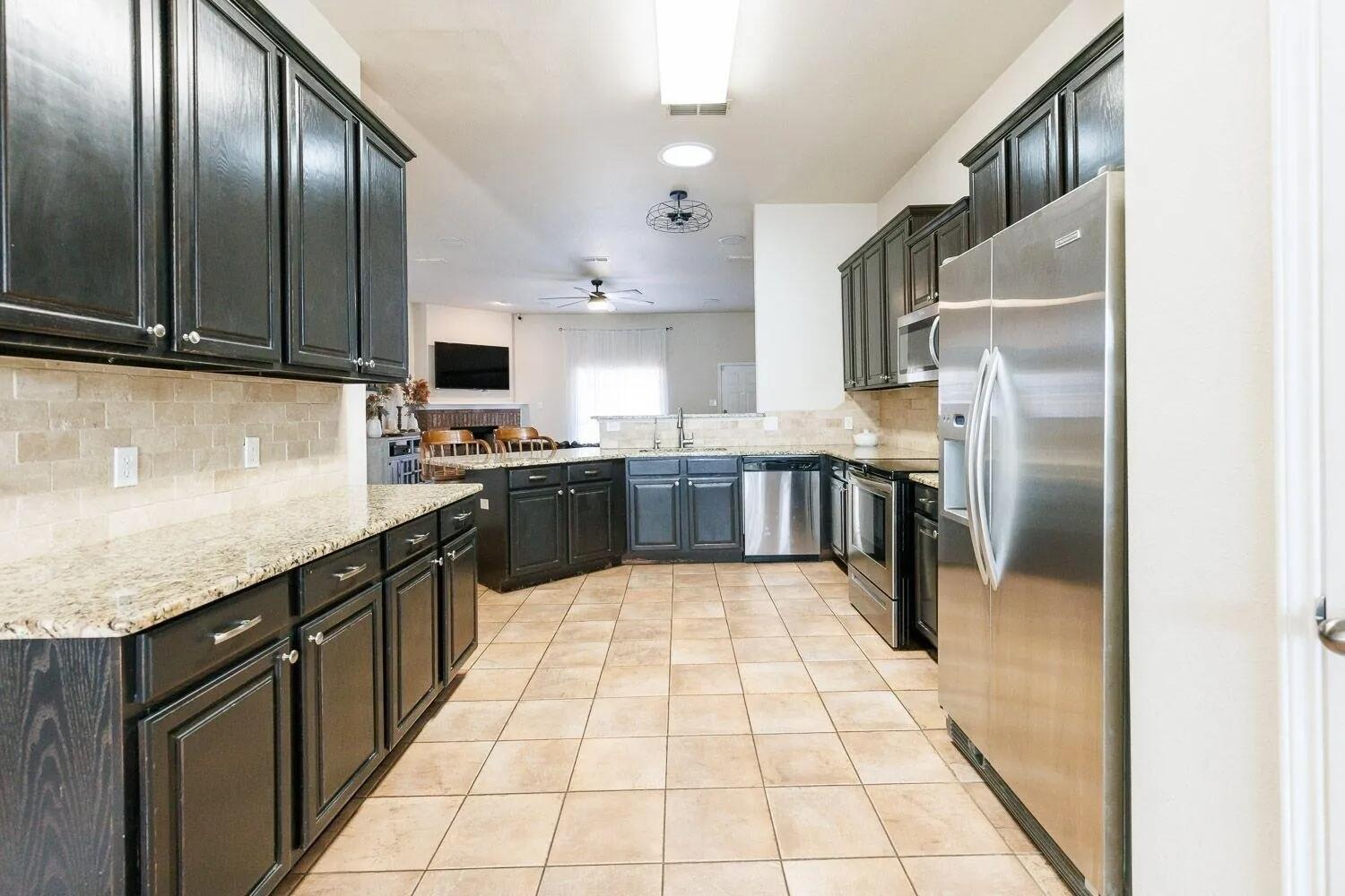 10602 Clinton Avenue Lubbock, TX 79424 - Photo 14 of 36 a large kitchen with stainless steel appliances granite countertop a sink stove and refrigerator