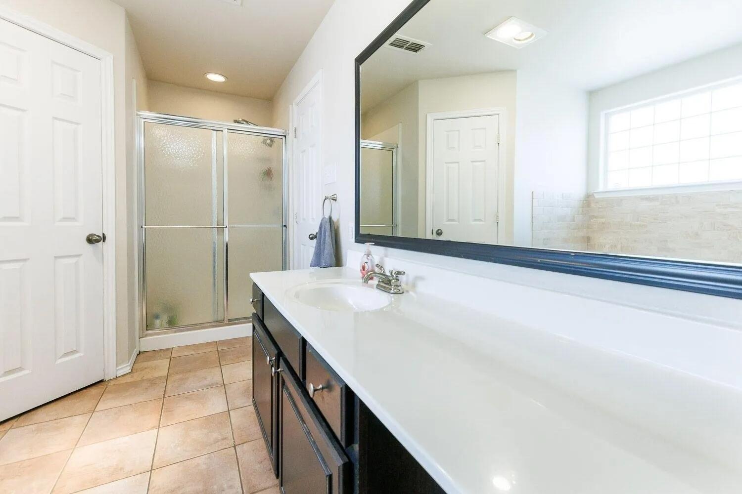 10602 Clinton Avenue Lubbock, TX 79424 - Photo 21 of 36 a bathroom with a double vanity sink a mirror and a bathtub