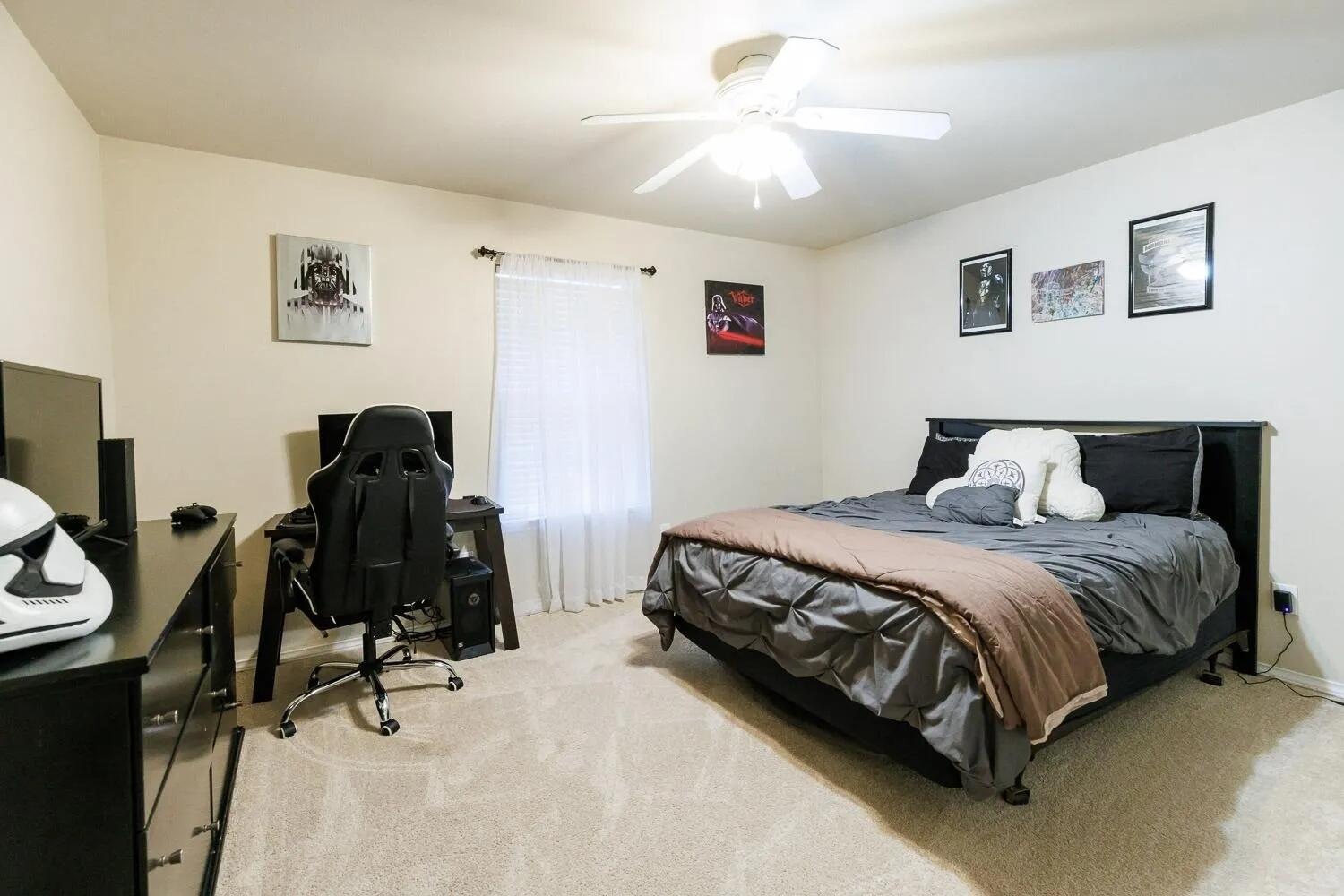 10602 Clinton Avenue Lubbock, TX 79424 - Photo 25 of 36 a bedroom with a bed and a chandelier