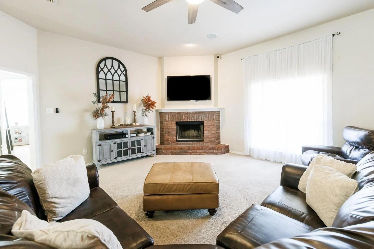 10602 Clinton Avenue Lubbock, TX 79424 - Photo 6 of 36 a living room with furniture a flat screen tv and a fireplace