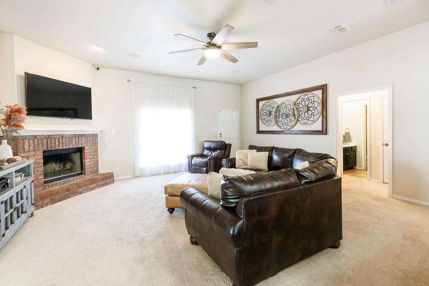 10602 Clinton Avenue Lubbock, TX 79424 - Photo 7 of 36 a living room with furniture a flat screen tv and a fireplace