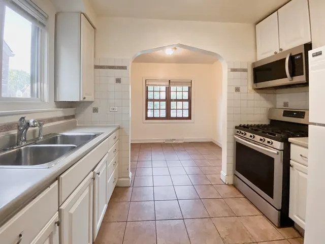 an empty room with wooden floor chandelier fan and windows