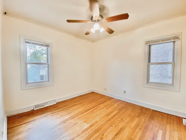 a view of empty room with wooden floor and fan