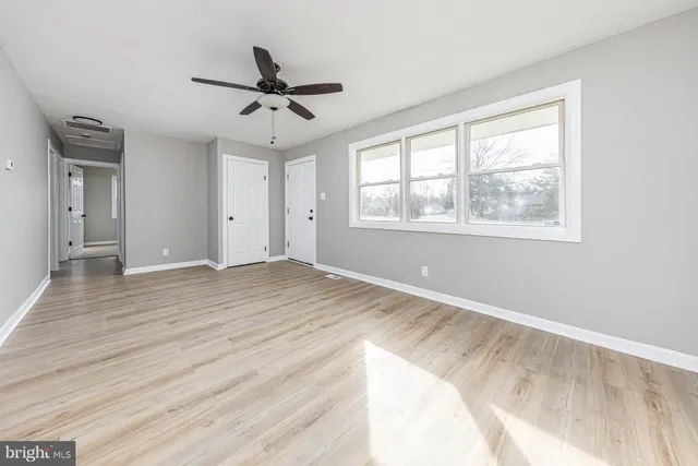 a view of empty room with wooden floor and ceiling fan
