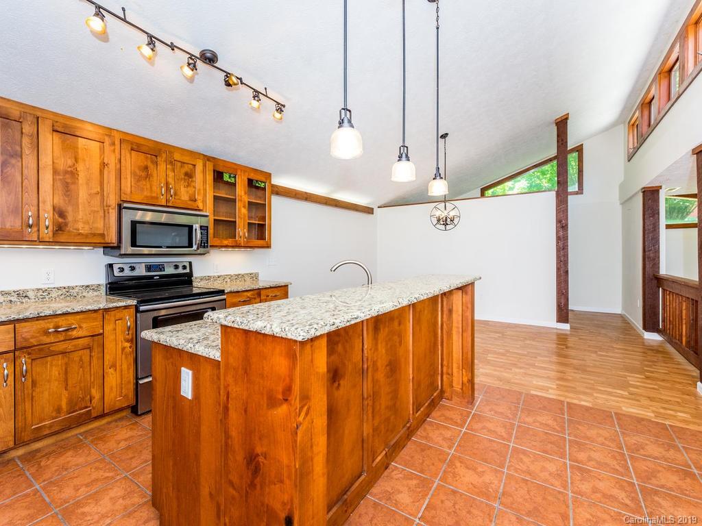 795 Springbrook Farm Road Waynesville, NC 28786 - Photo 12 of 45 a kitchen with stainless steel appliances granite countertop a sink a stove top oven a chimney cabinets and wooden floor