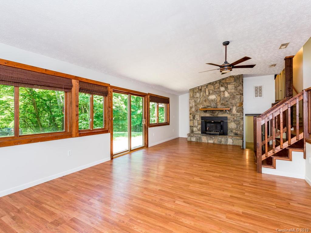 795 Springbrook Farm Road Waynesville, NC 28786 - Photo 4 of 45 a view of an empty room with window wooden floor and a fireplace