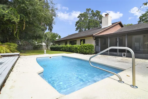 a view of a white house with a yard potted plants and a large tree