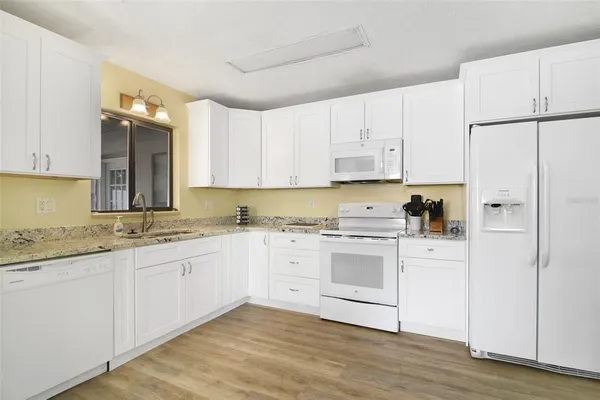 a kitchen with granite countertop white cabinets and white appliances