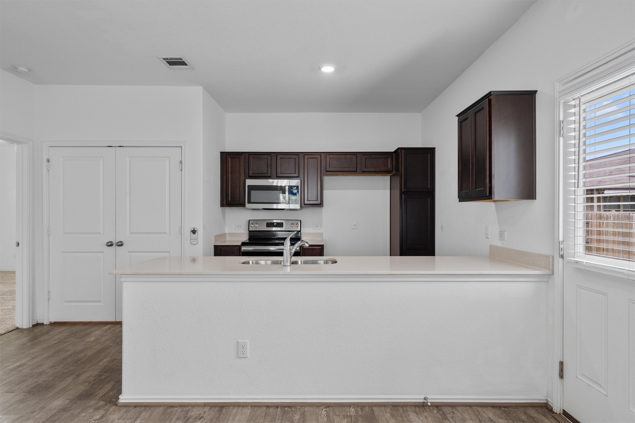 791 Circle Way Jarrell, TX 76537 - Photo 10 of 36 Kitchen featuring dark wood cabinetry, light countertops, stainless steel appliances, and a double-basin sink with a chrome faucet