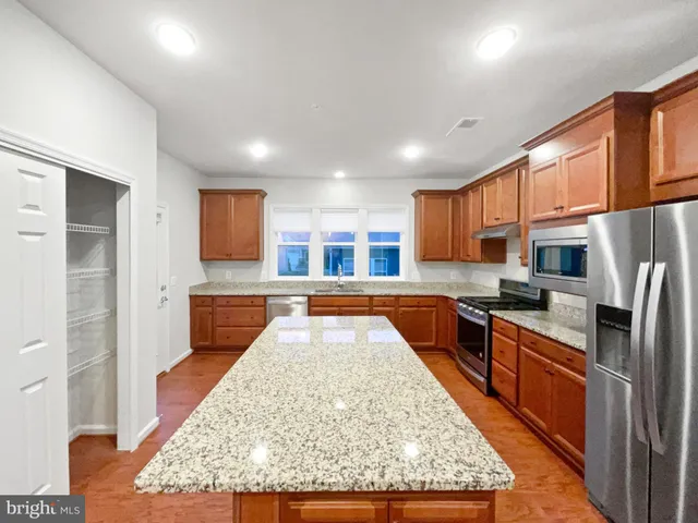 a large kitchen with kitchen island granite countertop wooden cabinets a granite counter and stainless steel appliances