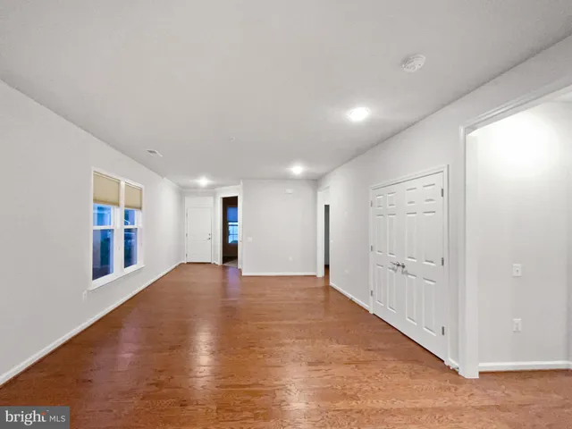 a view of an empty room with wooden floor and windows