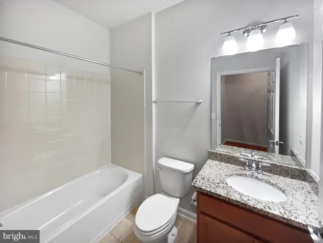 a bathroom with a granite countertop toilet sink and mirror