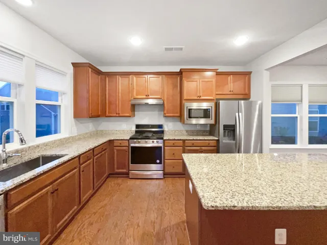 a kitchen with stainless steel appliances granite countertop wooden cabinets sink and stove