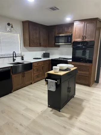 a kitchen with stainless steel appliances granite countertop wooden cabinets a stove a sink and a microwave