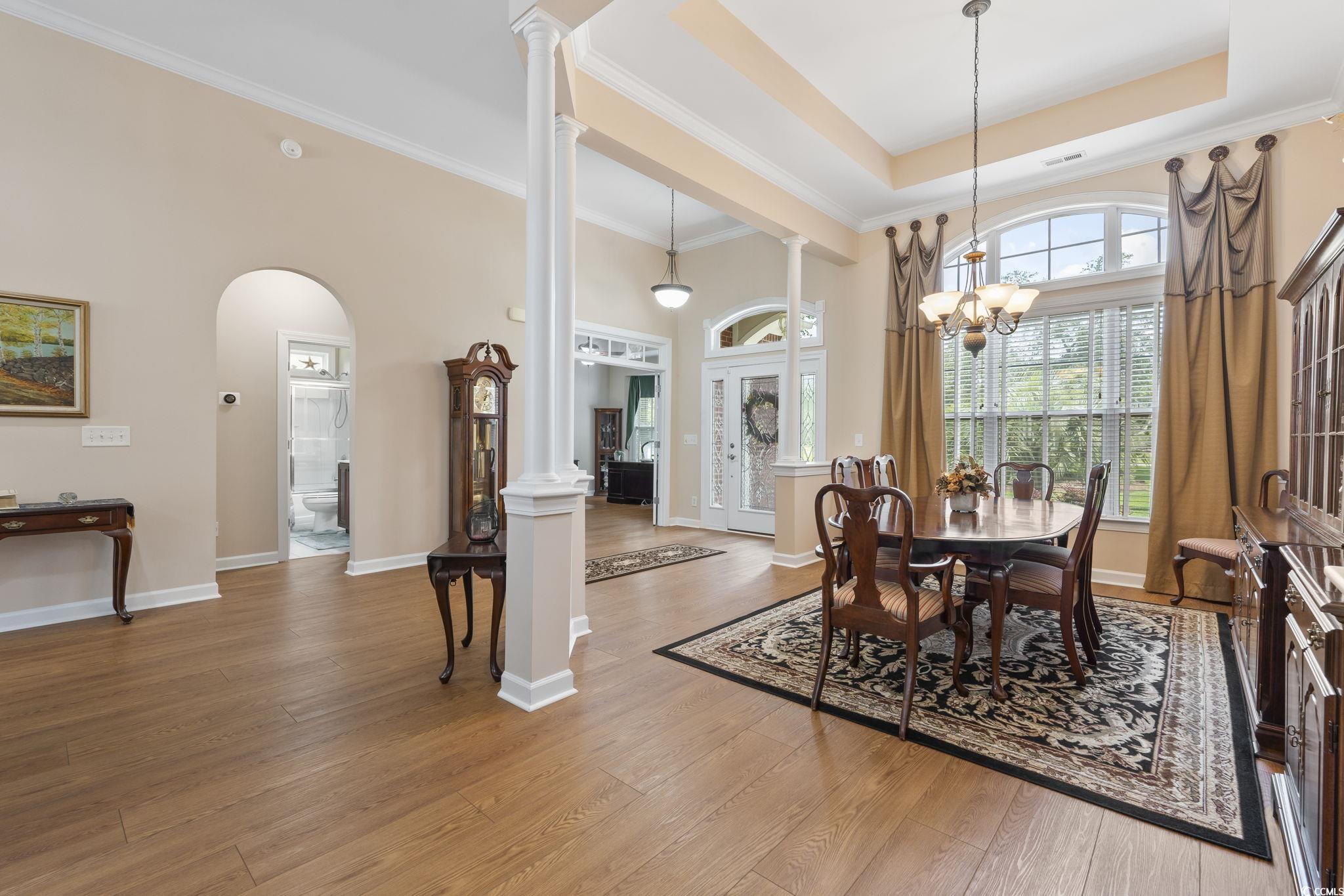 499 Trestle Way Conway, SC 29526 - Photo 14 of 40 Dining space featuring ornate columns, wood finished floors, arched walkways, a towering ceiling, and ornamental molding