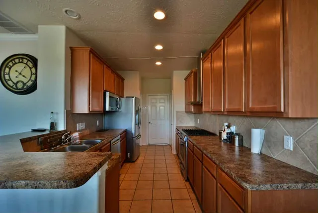 a kitchen with kitchen island granite countertop a sink a stove and cabinets