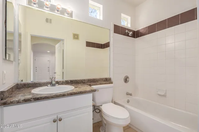 a bathroom with a granite countertop sink a toilet and shower
