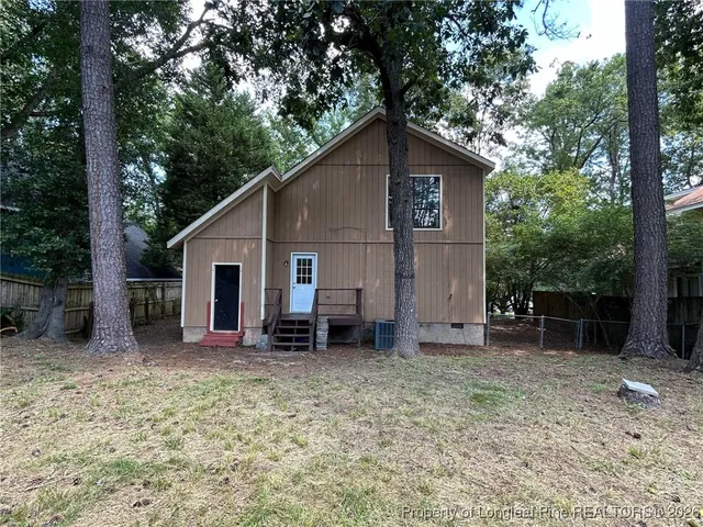 a house with a large tree and wooden fence