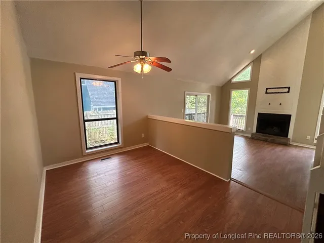 an empty room with wooden floor fireplace and windows
