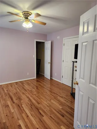 a view of an empty room with window a ceiling fan and wooden floor