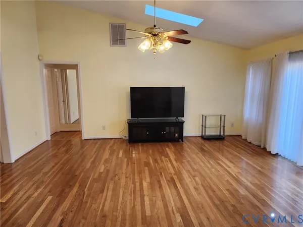a living room with hard wood floors and a flat screen tv