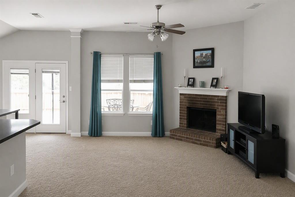 13153 Fencerow Road Fort Worth, TX 76244 - Photo 5 of 16 Carpeted living area featuring a brick fireplace with a white mantel, ceiling fan, and double patio doors