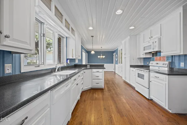 a large kitchen with stainless steel appliances granite countertop a lot of counter space and wooden floors