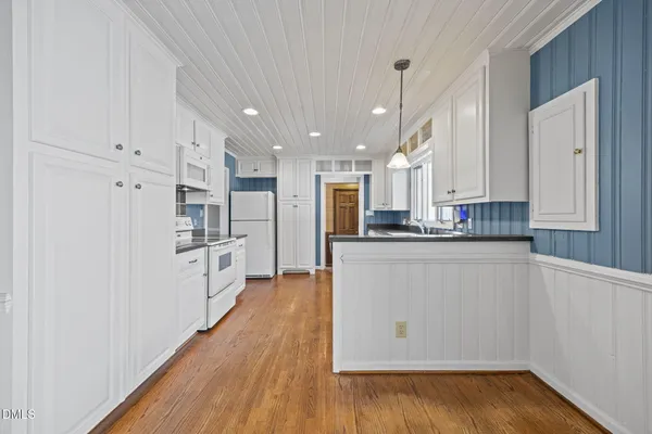 a kitchen with stainless steel appliances granite countertop a refrigerator a sink and white cabinets with wooden floor