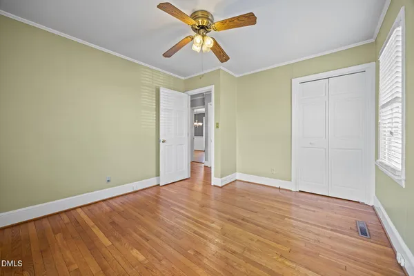 an empty room with wooden floor chandelier fan and windows