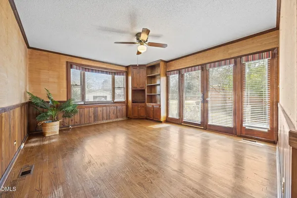 a view of an empty room with wooden floor and a window
