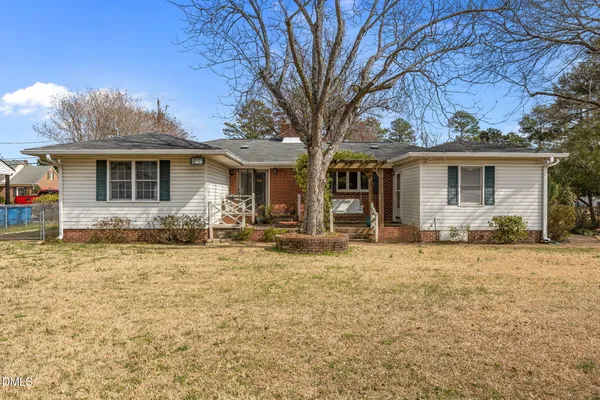 a front view of house with yard and trees in the background