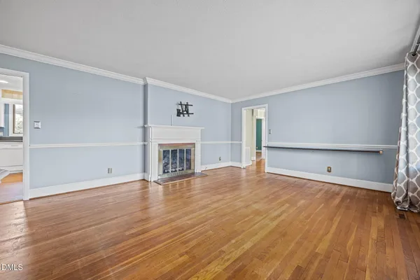 an empty room with wooden floor fireplace and windows