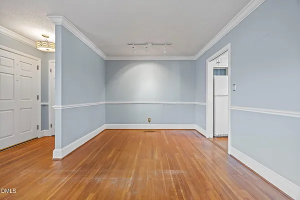 a view of an empty room with wooden floor and closet