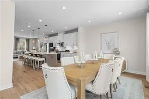 a dining room with stainless steel appliances kitchen island granite countertop a dining table chairs and white cabinets