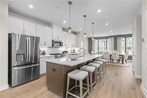 a kitchen with stainless steel appliances granite countertop a refrigerator a sink dishwasher a stove and white cabinets with wooden floor