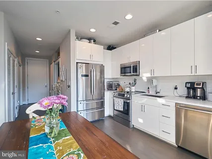 a kitchen with stainless steel appliances kitchen island granite countertop a refrigerator stove microwave and cabinets