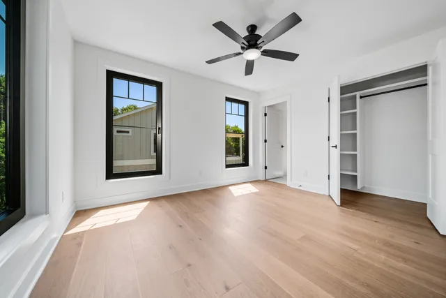 an empty room with wooden floor and ceiling fan