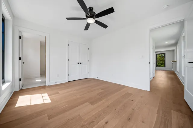 a view of empty room with wooden floor and fan