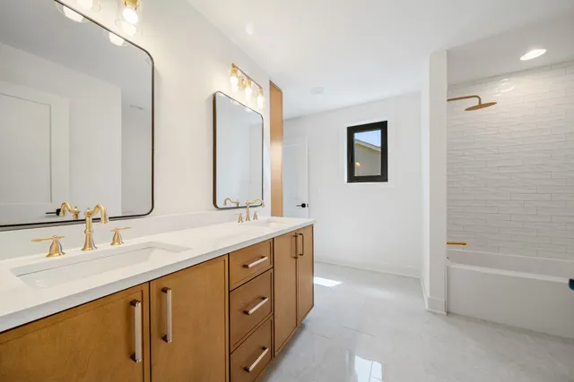 a bathroom with a double vanity sink a mirror and a bathtub