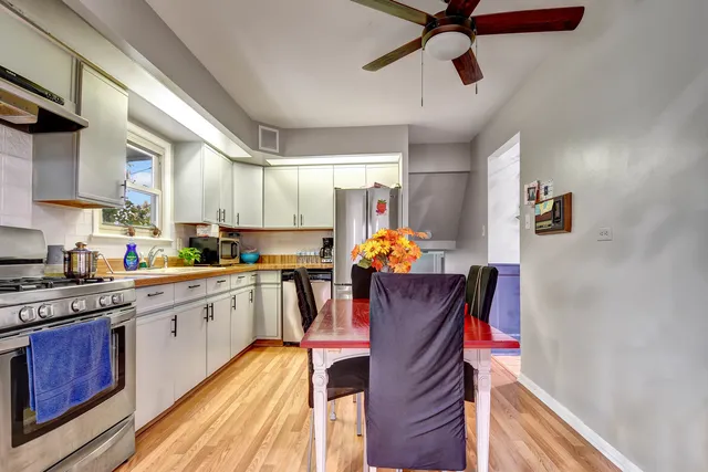 a kitchen with stainless steel appliances granite countertop a refrigerator a sink dishwasher a stove and white countertops with wooden floor