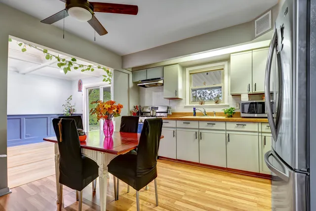a kitchen with stainless steel appliances granite countertop a dining table chairs and a refrigerator