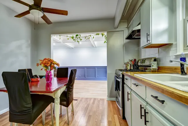 a kitchen with stainless steel appliances granite countertop a dining table chairs wooden floors and a stove