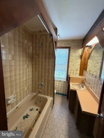 a bathroom with a tub a sink and a large mirror