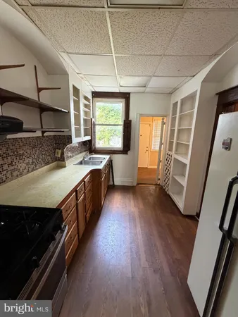 a kitchen with a sink stove and wooden floor