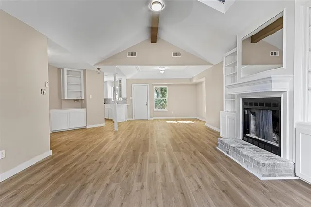 a view of empty room with wooden floor and fireplace